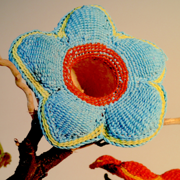 5 petaled flower made of light blue yarn with a red center